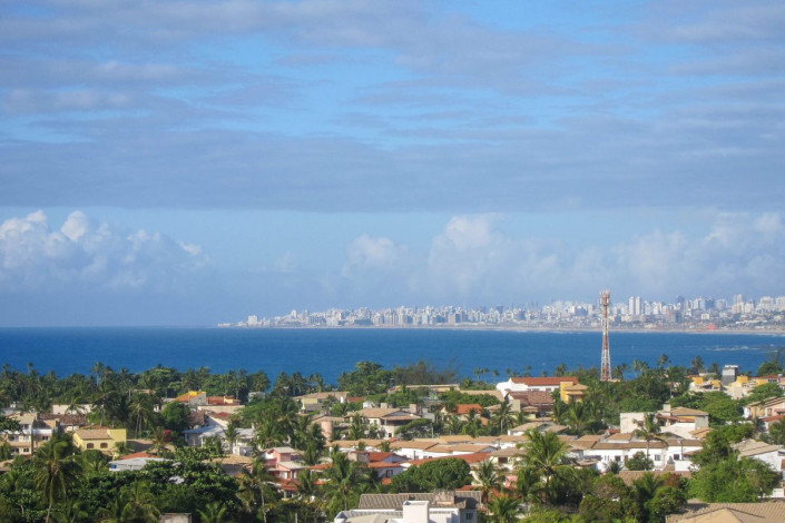 Blick über die palmengesäumte Küste Brasiliens mit dem Praia da Itapuã bis zum Stadtzentrum von Salvador