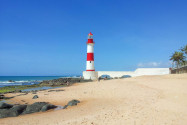 Der rot-weiß gestreifte Farol de Itapuã passt genau ins Bild eines malerischen Strandes und ist ein beliebtes Fotomotiv am Praia da Itapuã, Salvador, Brasilien - © FRASHO / franks-travelbox
