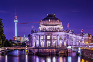Hinter der Museumsinsel von Berlin ragt der Fernsehturm auf dem Alexanderplatz spektakulär beleuchtet in den Nachthimmel Deutschlands