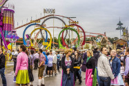 Münchner Oktoberfest - im HIntergrund der Olympia Looping, die größte mobile Achterbahn der Welt, Deutschland - © anandoart / Shutterstock