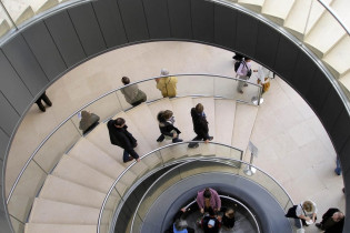 Ein Stiegenhaus führt den Besucher nach unten in eine große Halle, in der Informationsbroschüren und Folder in zahlreichen Sprachen aufliegen, Louvre, Paris, Frankreich