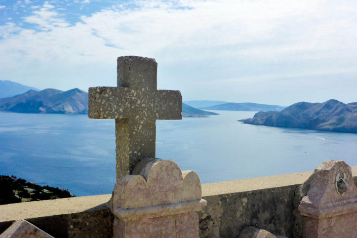 Die steinernen Grabmäler und Kreuze um die Johanneskirche verleihen dem idyllischen Blick auf die Baska-Bucht einen schaurig-schönen Hauch, Krk, Kroatien