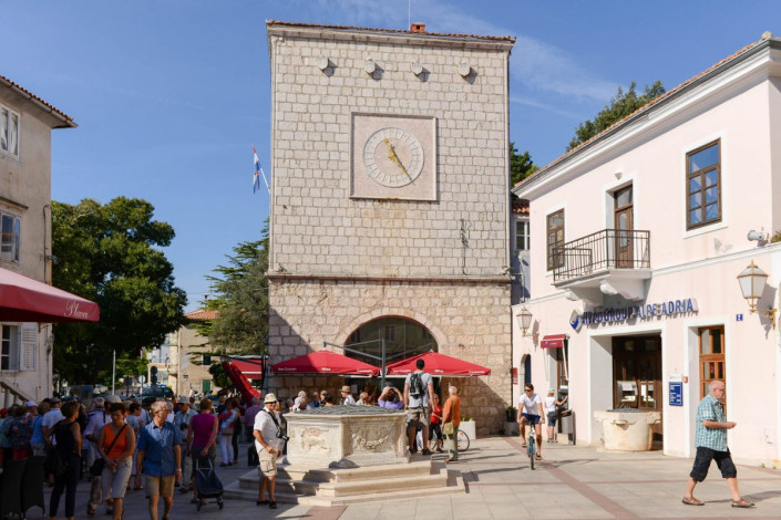 Neben Verwaltungsgebäuden sind am Placa Vela in Krk Stadt auch zahlreiche Cafés und jede Menge Touristen zu finden, Kroatien