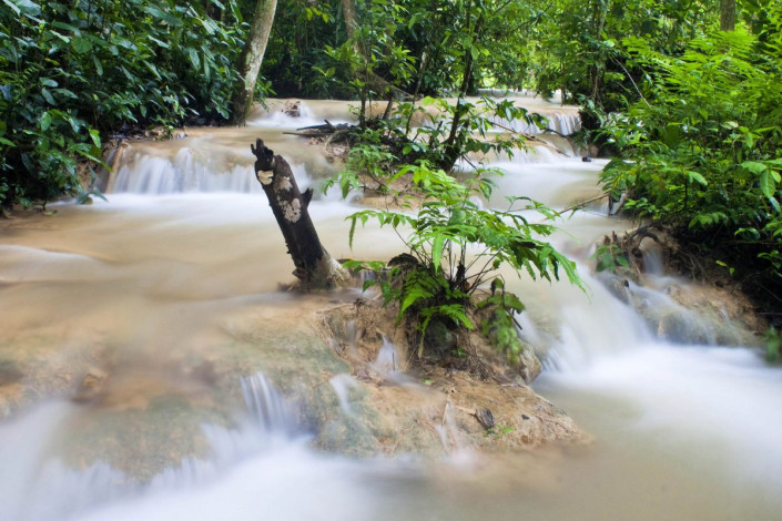 Die Formation der Kuang Si Wasserfälle in Laos wechseln zwischen steilen Hängen und flachen Passagen mit ruhigem Wasser