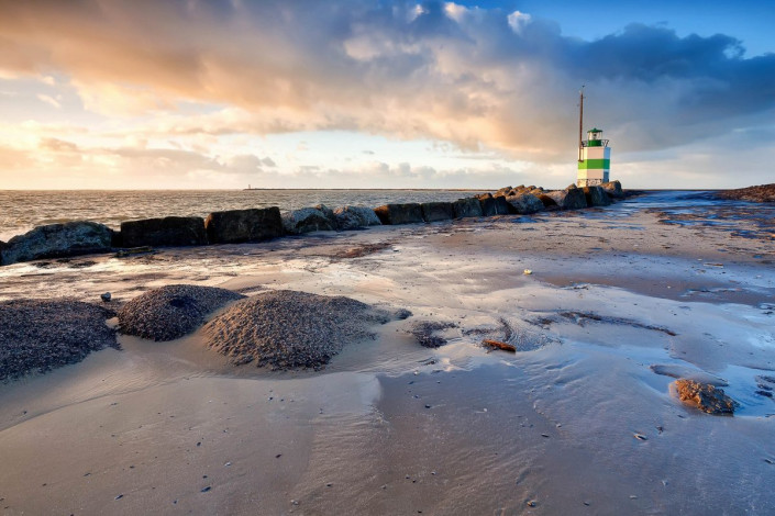 Der Leuchtturm an der niederländischen Nordseeküste in Ijmuiden wird von der untergehenden Sonne in romantisches Licht getaucht