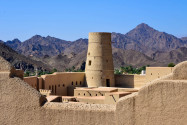 Die hellen, sandfarbenen Mauern der Festung von Bahla heben sich deutlich vor dem dunklen Hintergrund des gewaltigen Gebirgszuges Jebel Akhdar ab, Oman - © FRASHO / franks-travelbox