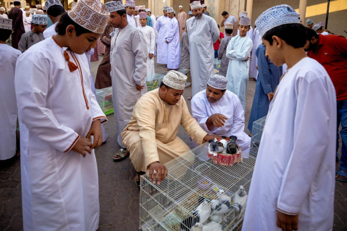 Junge Burschen stehen am Tiermarkt von Nizwa um die Männer herum um zu lernen und bald selbst in die Geschäfte einsteigen zu können, Oman