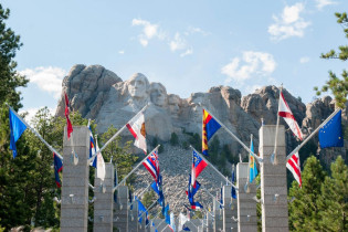 Am Mount Rushmore wird der Besucher von einer Allee aus Flaggen begrüßt, die direkt zur Aussichtsplattform unter den Präsidentenköpfen führen, USA