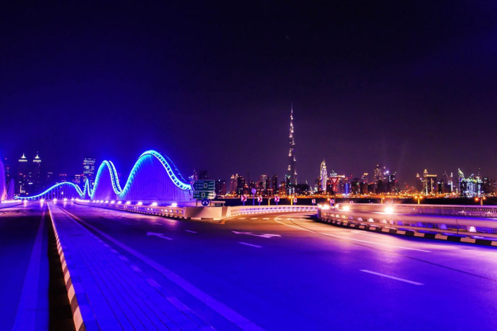 Blick auf die nächtlich beleuchtete Meydan Rennstrecke mit der Skyline von Dubai im Hintergrund, VAE