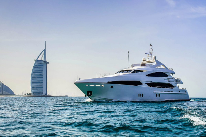 Eine Luxusyacht auf dem Weg in die Dubai Marina, vorbei am berühmten Hotel Burj al Arab, VAE