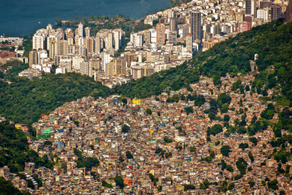 Luftbild der Favela da Rocinha am Hang in Rio de Janeiro, dahinter die Skyline der Stadt, Brasilien