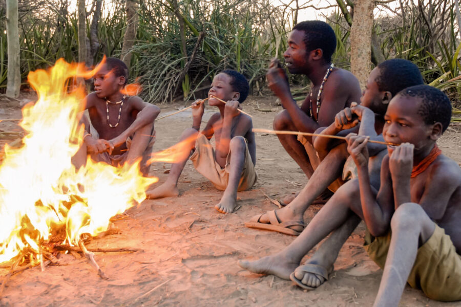 Eine Gruppe Buschmänner des Hadzabe-Stammes sitzt am Feuer in der Nähe des Lake Eyasi in Tansania - © pcruciatti / Shutterstock