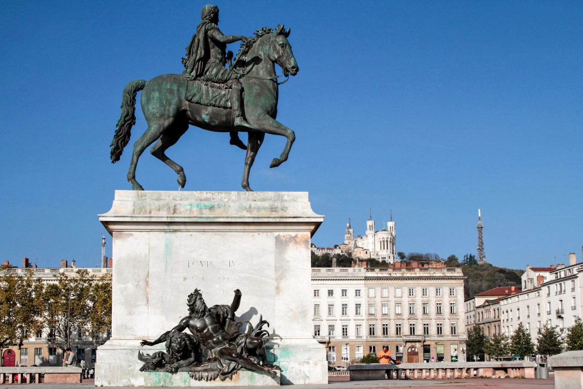 Trotz seiner riesigen Fläche ist der Place Bellecour in Lyon, Frankreich, für Fußgänger reserviert, die gemütlich am Reiterdenkmal von Ludwig XIV. vorbei flanieren