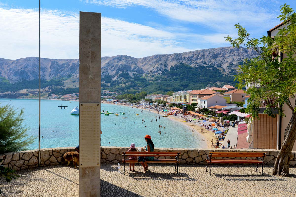 Gemauerte Aussichtspunkte eröffnen immer wieder herrliche Panoramen über das bunte Treiben am Strand von Baska, Krk, Kroatien