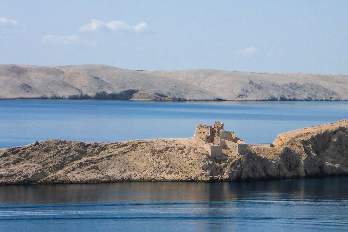 Auf der kargen Insel Pag vor der Küste von Kroatien ragen die Ruinen einer alten Festung aus dem sandfarbenen Karstgestein