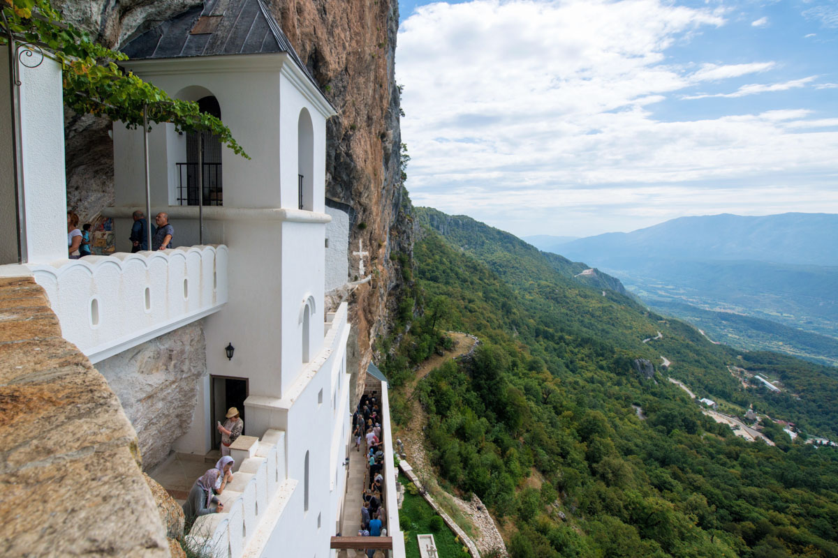 Der Panoramablick von der steilen Bergflanke des Felsenklosters Ostrog reicht kilometerweit über die Bjelopavlićko-Ebene in Montenegro