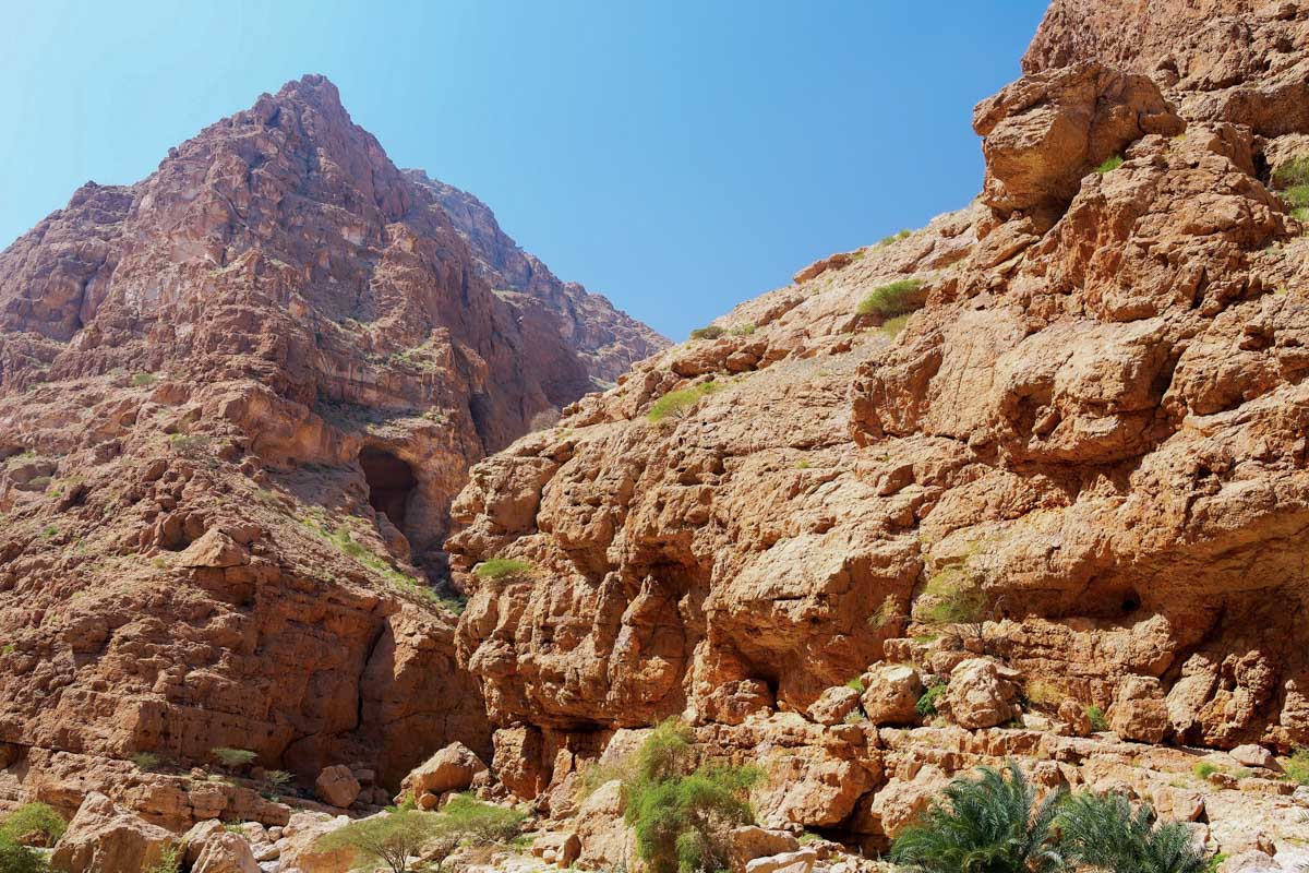 In den zerklüfteten Felswänden, die um das Wadi Shab aufragen, verbergen sich Höhlen und Felsspalten, Oman