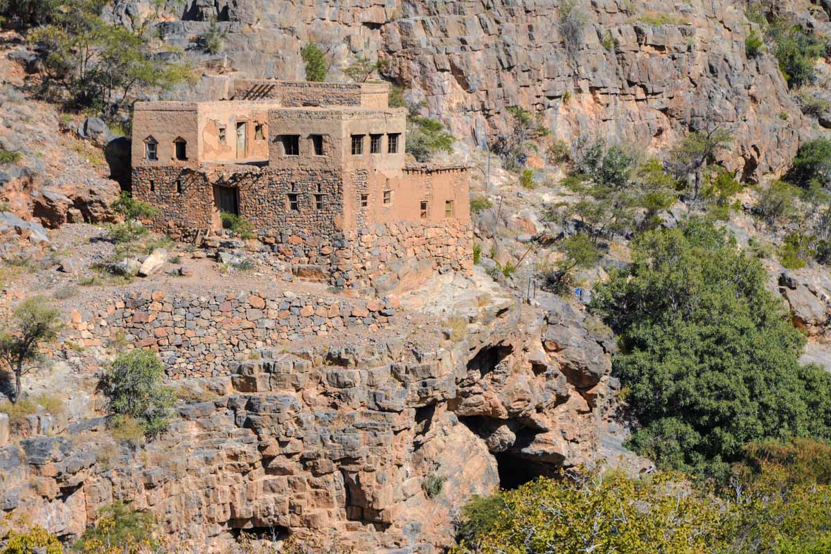 Die teilweise verwitterterten Lehmhütten im Wadi bani Habib schmiegen sich wie Spielzeughäuschen an die steile Flanke des Berges, Oman