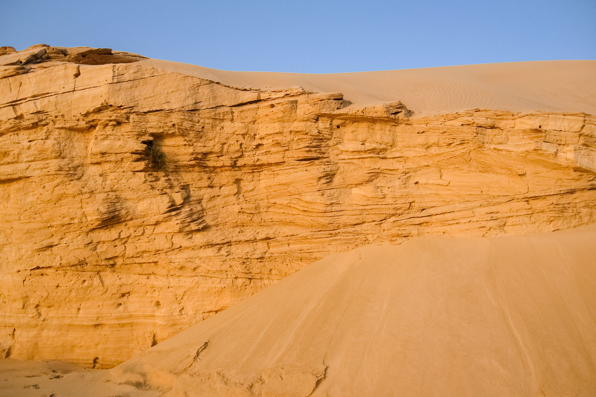 An der Abbruchkante der Wahiba Sands beim arabischen Meer sieht man die gepressten Sandschichten unter den Dünen, Oman