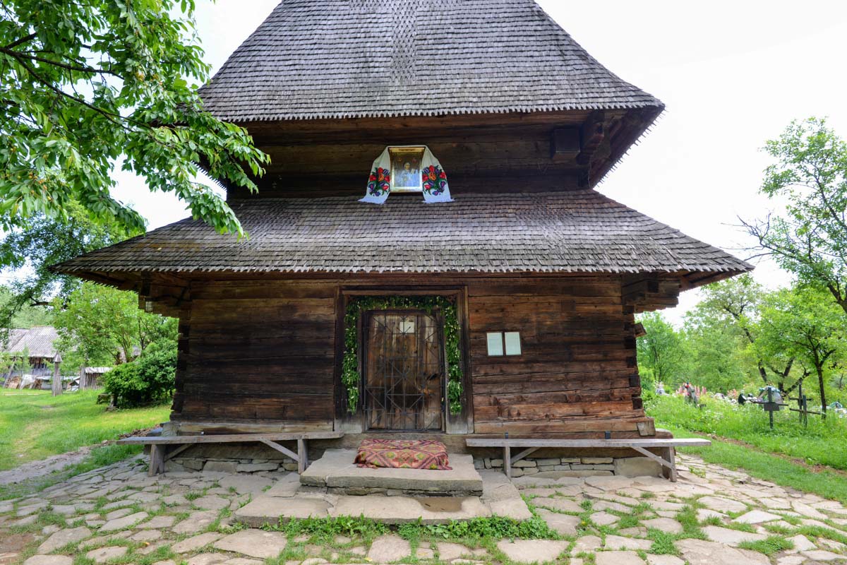 Unter dem gewaltigen Schindeldach scheint der Kirchenraum der Holzkirche von Deseşti nahezu zu verschwinden, Rumänien