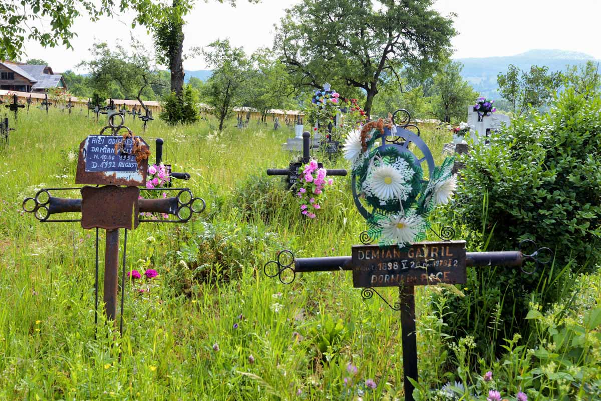 Am Friedhof rund um die Holzkirche von Șurdești in Rumänien ragen zahlreiche steinerne, eiserne und hölzerne Kreuze aus der Wiese